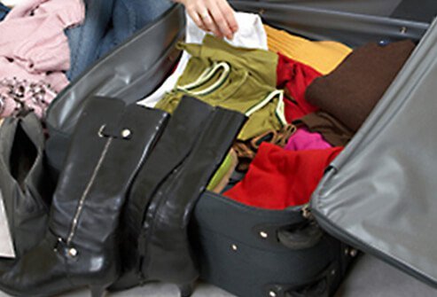 Woman deciding which clothes to pack in suitcase as well as what to keep with her.