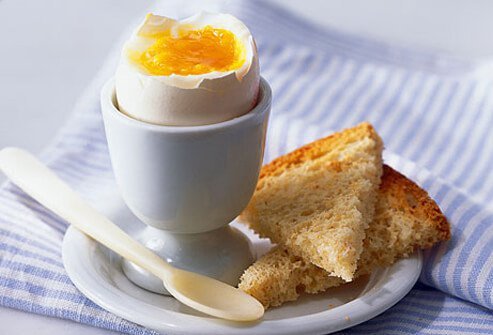 Boiled egg in a cup with wheat toast.