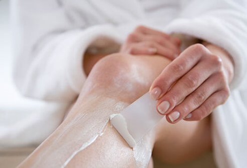 Photo of woman removing hair from her legs.