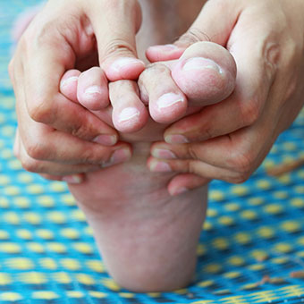 A person checks their toes for corns and calluses.