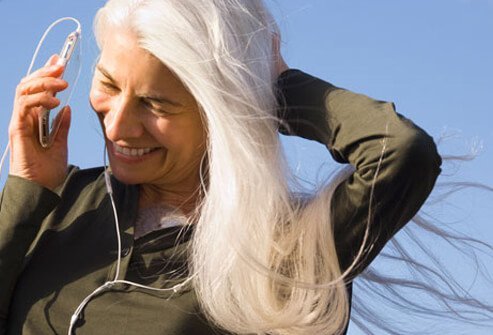 Photo of an older, happy woman listening to music.