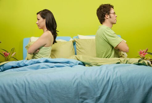 Photo of angry couple back to back in bed.