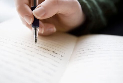 Photo of a person writing in journal.