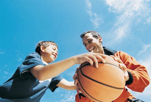 Photo of a father and son playing basketball.