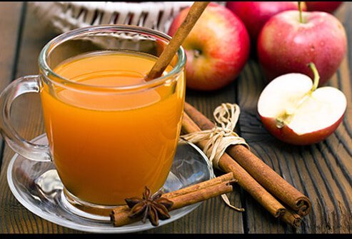 A glass of spiced apple cider with cinnamon sticks.