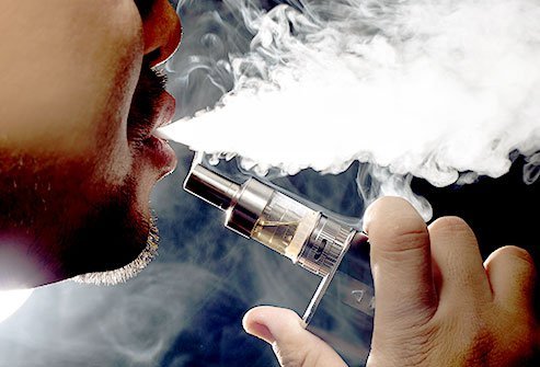 Bearded man vaping an e-Cigarette and blowing vapor