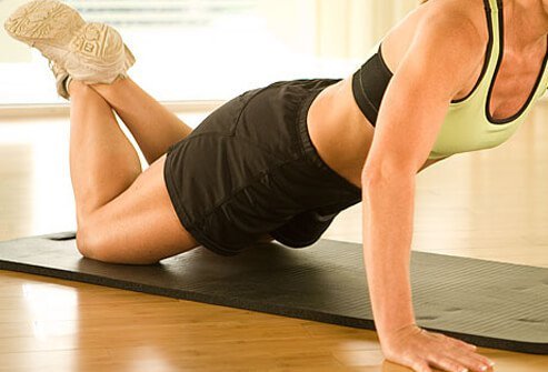 A trainer demonstrating a push-up on the knees.