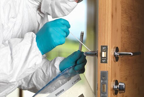 A scientist swabs a door handle for a germ sample.