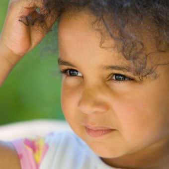 A little girl scratches her head.