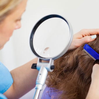 A nurse inspects a child's head for lice.