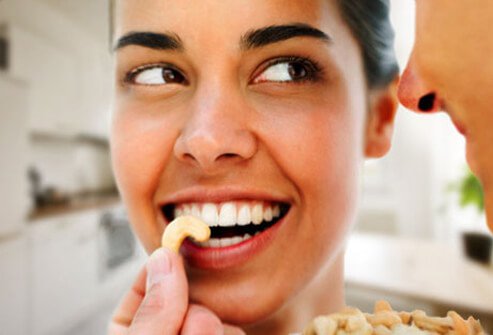 Photo of woman eating good fats (cashews).