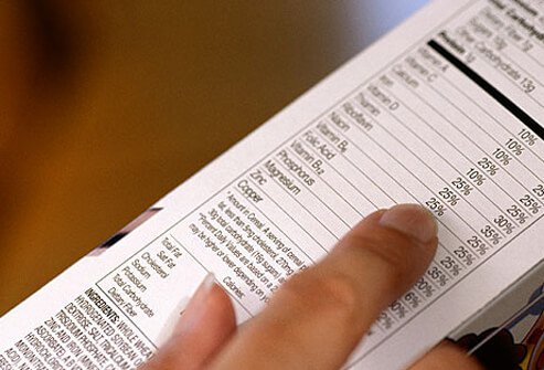 Photo of woman reading nutrition label.