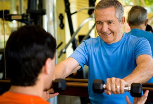 A senior man weight training with a personal trainer.