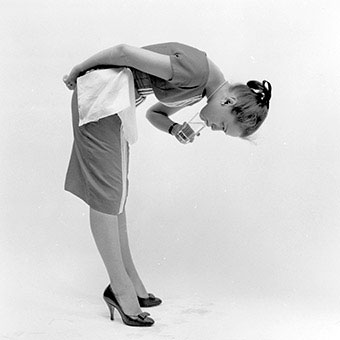 A woman drinks from the opposite edge of the glass.