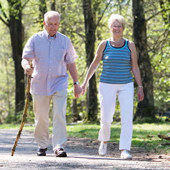 An elderly couple walks through the park.