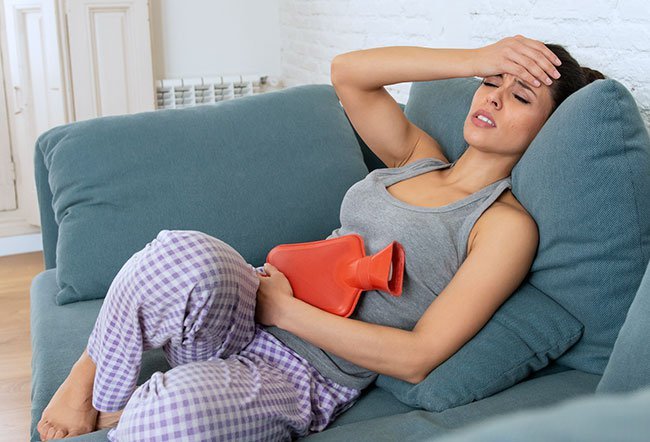 Signs your period is coming include tender breasts, headaches, abdominal cramps, muscle aches, lower back pain, fatigue, bloating, joint pain, acne, and diarrhea or constipation.