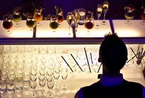 Photo of a bartender at an illuminated bar at night.