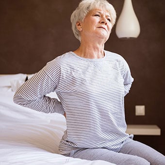 A woman presses into her back due to kidney pain.