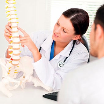 A doctor explains the lower spinal structures of the back to her patient.