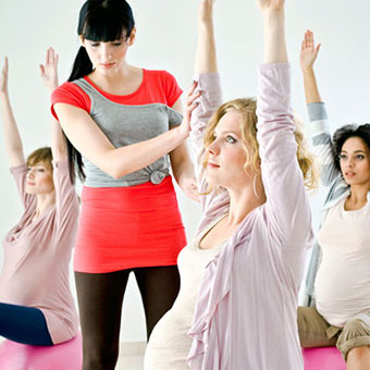 Pregnant women exercise on gym balls with their physical trainer.