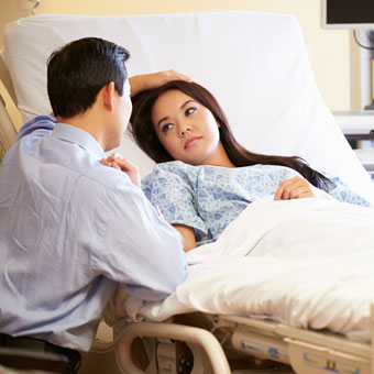 A husband comforts his wife in the hospital.