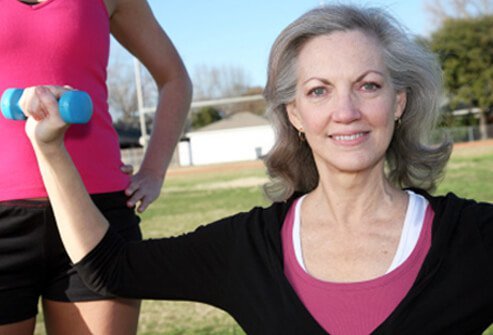 A woman exercises with light weights.
