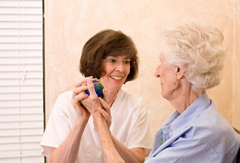 A nurse instructs a senior woman on how to exercise.