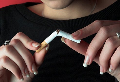 A woman breaks her cigarette in half.