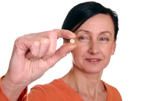 A woman takes her hormone therapy pill.