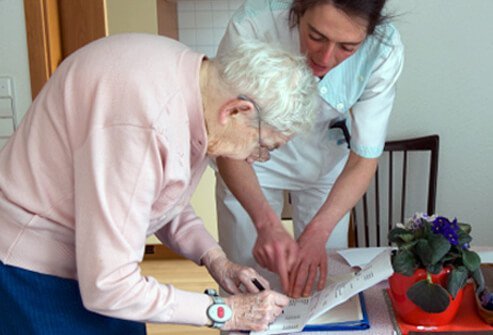 A senior woman with osteoporosis signs documents for a nurse.