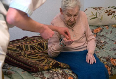 A nurse helps a senior woman with osteoporosis stand up.