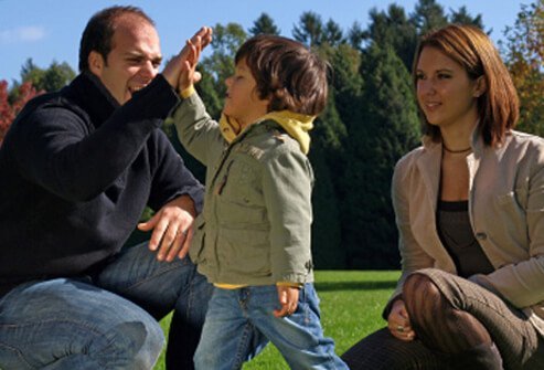 A father and son high-five each other as mom watches.
