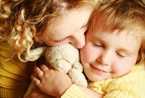 A mother snuggles with her daughter. 