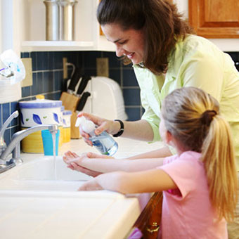 A mother and daughter wash their hands.