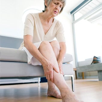 An older woman rubbing her aching legs due to restless leg syndrome.