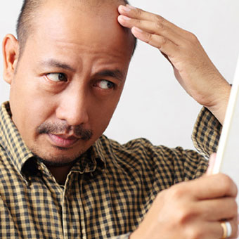 A man uses a mirror to examine his head for ringworm.