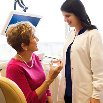 A dentist and patient discuss oral health treatments such as dentures as an alternative to a root canal.