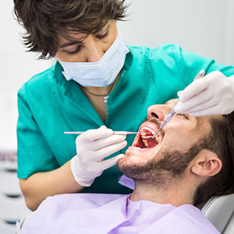 A dentist performs an oral health exam on the teeth of a patient.