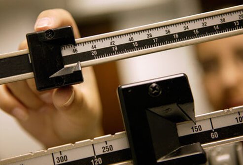 A woman checking her weight on a scale.