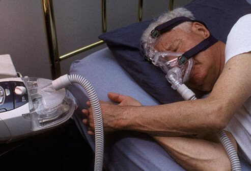 A man sleeping with a CPAP device, treating a sleep disorder.