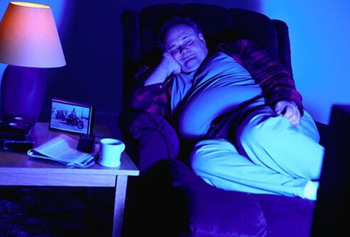 A man with poor sleep hygiene asleep in front of a television.