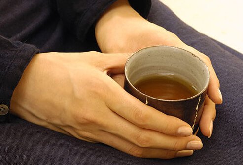 Women holding a hot glass of black tea.