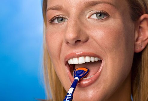 A woman brushing her tongue. 
