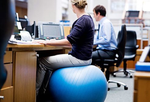 Photo of woman sitting at her desk on a posture enhancing ball.