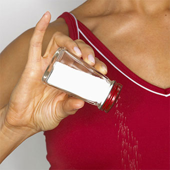 A woman pours salt out of a salt shaker.
