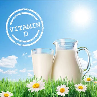 Vitamin D stamp on image with the sun, a jug, and glass of milk on the grass with daisies.
