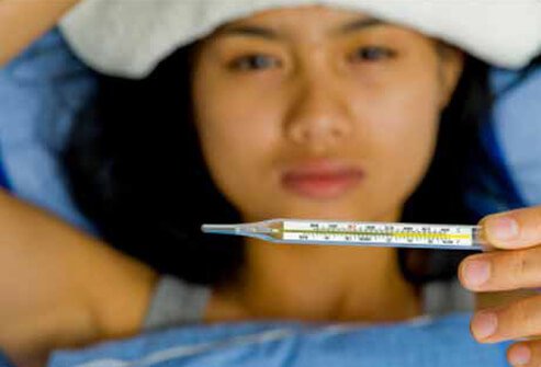 A woman sick in bed with a headache and fever