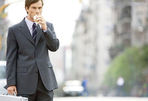 A man eating a sandwich while walking to work.