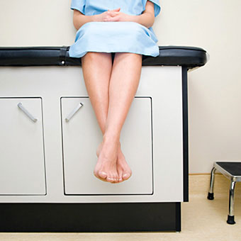 A woman waits in a doctor's medical exam room.